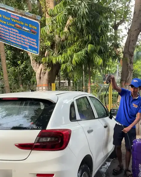 Washer rinsing a white hatchback next to the GH-9 RWA parking notice