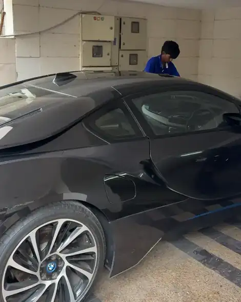 Washer drying a black BMW i8 in a covered parking