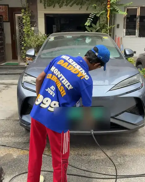 Washer rinsing an electric car, his shirt reads Monthly carwash at just 999
